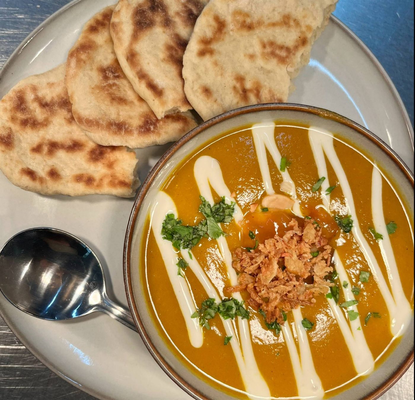 A bowl of soup served with warm flatbread